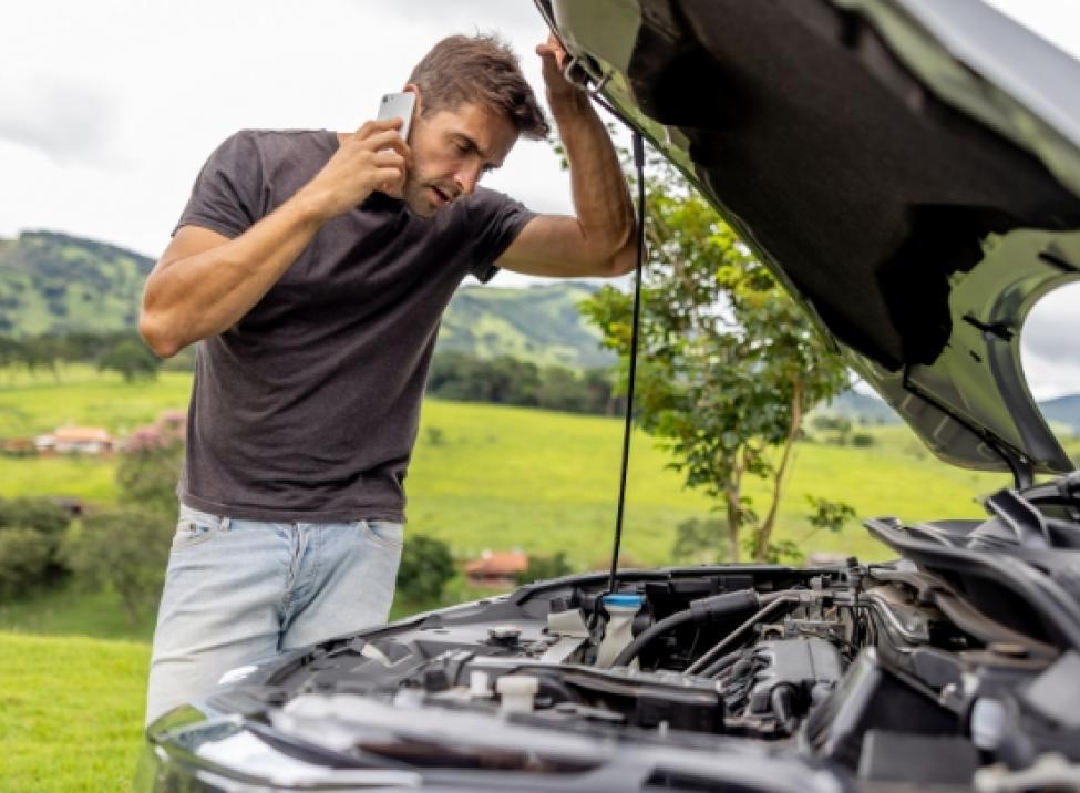 Customer on phone observing engine bay under car hood