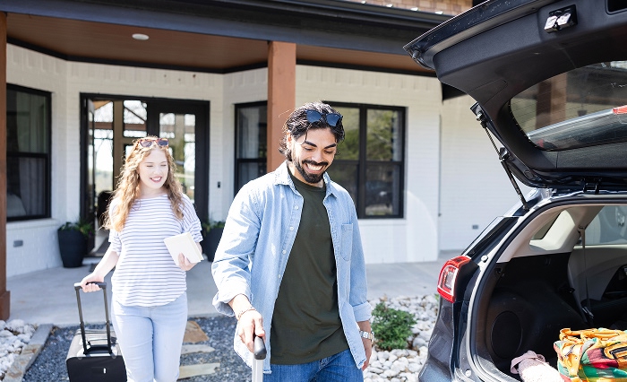 Family loads up their car in the driveway of the home they own