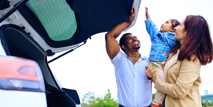Happy family opening the back of their personal SUV